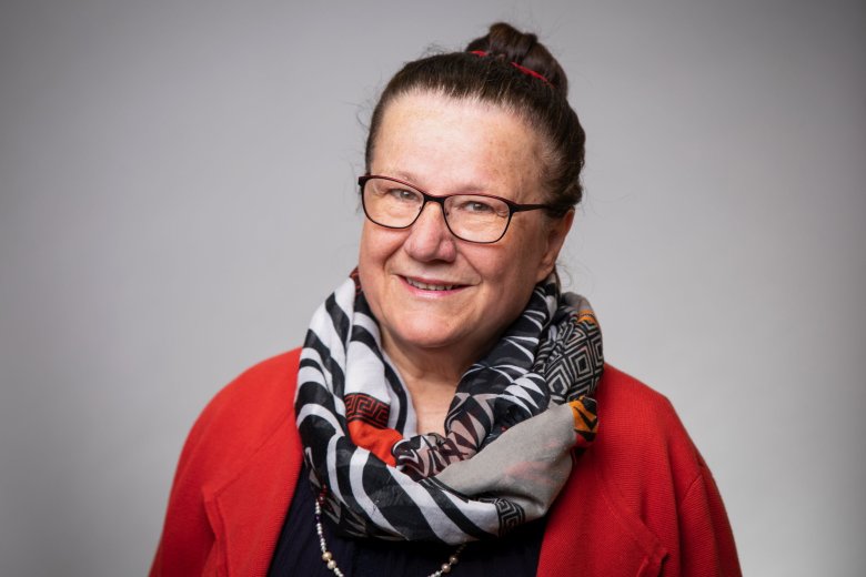 Eine Frau mit Dutt, Brille, einem Afrikanischem Schal und rotem Pullover