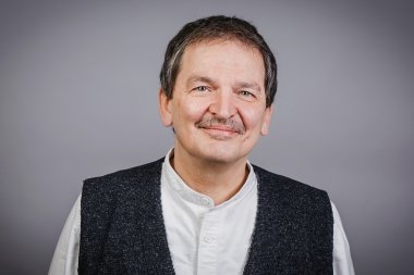 Ein dunklehaariger Herr mit einem hellen Hemd und einer schwarzen Weste